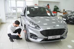 une homme examine une voiture dans une voiture concession photo