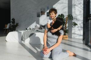 maman est étreindre sa fils séance sur le sol dans le chambre. famille Accueil tirer. photo