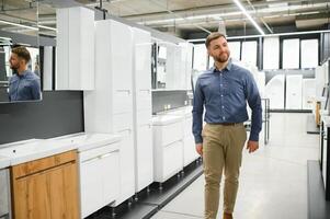 homme choisir Nouveau salle de bains meubles à le plomberie magasin avec beaucoup de sanitaire des biens photo