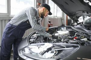 professionnel mécanicien est travail sur une voiture dans une voiture service. photo