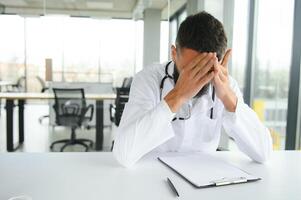 portrait de épuisé fatigué Jeune arabe Masculin médecin après difficile journée à travail photo