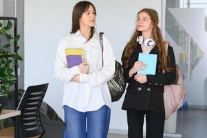 souriant les filles dans haute école couloir. deux femelle Université élèves parlant après conférence. photo