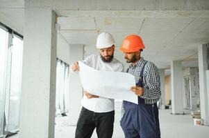 Indien et arabe ingénieurs. prestataire et architecte parlant à propos travail sur gros projet. bâtiment dans construction processus intérieur. photo