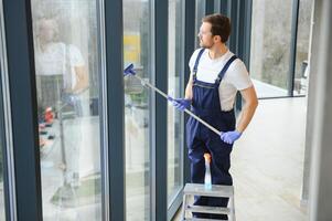 un employé de une professionnel nettoyage un service lavages le verre de le les fenêtres de le bâtiment. vitrine nettoyage pour magasins et entreprises. photo