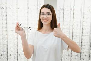 Jeune magnifique fille dans des lunettes près le supporter dans le optique magasin. émotions. ophtalmologie. photo