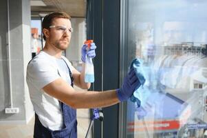 un employé de une professionnel nettoyage un service lavages le verre de le les fenêtres de le bâtiment. vitrine nettoyage pour magasins et entreprises. photo