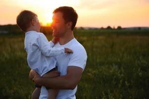 Jeune père jette en haut le sien mignonne et peu fils dans le Frais air. du père jour, père et le sien fils bébé garçon en jouant et étreindre en plein air. photo