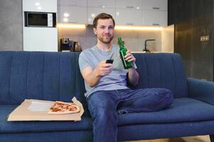 mange Pizza tandis que en train de regarder la télé montrer. homme avec barbe à l'intérieur. photo