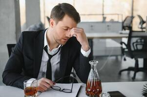 alcoolisme à travail. fatigué employé en buvant de l'alcool à lieu de travail, pouvez ne pas manipuler stress. photo