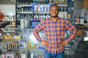 portrait de une Beau africain vendeur dans un auto les pièces magasin. le concept de voiture réparation photo