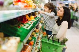 femme et enfant garçon pendant famille achats avec chariot à supermarché photo