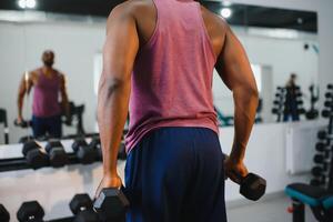 content africain homme en utilisant Stationnaire vélo dans une salle de sport. photo