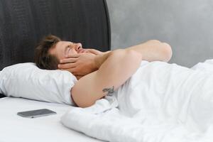 Jeune homme dans lit , en essayant à sommeil photo