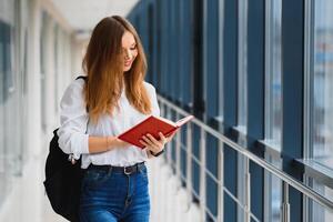 positivité magnifique fille souriant à caméra, permanent sur couloir avec Remarques comme sac à dos, Aller à leçon. content brunette femelle étudiant en train d'étudier dans luxe université. photo