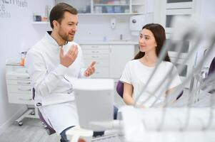 personnes, médecine, stomatologie et santé se soucier concept - femme patient parlant à Masculin dentiste et se plaindre de mal aux dents à dentaire clinique bureau. photo