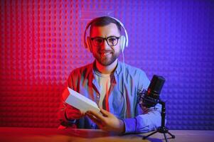 Jeune homme enregistrement ou diffusion Podcast en utilisant microphone à le sien petit diffuser studio. contenu créateur. photo