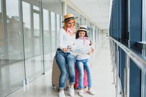 mère et peu fille avec bagage et carte à aéroport Terminal prêt pour vacances. photo