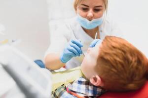 peu garçon ayant le sien les dents examiné par une dentiste photo