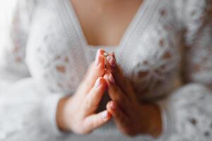 la mariée détient mariage bague sur sa main contre le Contexte de une blanc dentelle mariage robe. corps les pièces, tenir mains. photo