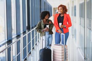 plein longueur côté portrait de Jeune noir femme en marchant avec valise dans aéroport photo