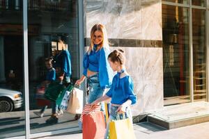 vente, consumérisme et gens concept - content Jeune femmes sa dauther avec achats Sacs en marchant ville rue. photo