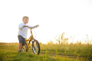 une Beau garçon avec vélo dans le été champ. photo