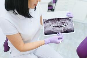 dentiste expliquant le détails de une radiographie les dents image à le sien patient dans clinique. oral se soucier, orthodontie. photo