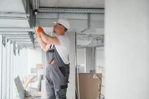 homme réglage en haut ventilation système à l'intérieur. une Masculin ouvrier installe air ventilation tuyaux dans une Nouveau Bureau bâtiment. photo