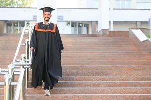 Jeune Indien diplômé garçon en portant le sien l'obtention du diplôme diplôme convocation cérémonie. étudiant diplômé posant. photo