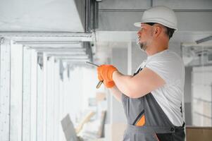 homme réglage en haut ventilation système à l'intérieur. une Masculin ouvrier installe air ventilation tuyaux dans une Nouveau Bureau bâtiment. photo