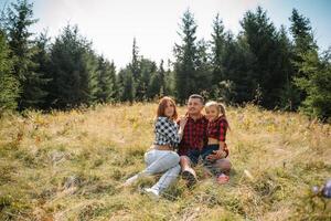 famille de Trois gens du repos dans le montagnes. elles ou ils Sam vers le bas à repos, boisson l'eau après une difficile montée à le Montagne. elles ou ils sont fatigué mais content photo