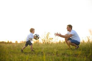 Jeune père avec le sien peu fils en jouant football, du père journée. photo