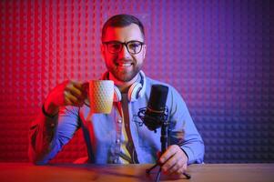 Jeune homme enregistrement ou diffusion Podcast en utilisant microphone à le sien petit diffuser studio. contenu créateur. photo