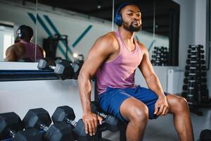 noir athlète fléchissement muscles, démontrant fort biceps dans Gym photo