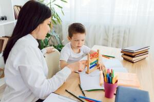 femelle privé tuteur portion Jeune étudiant avec devoirs à bureau dans brillant enfant pièce photo