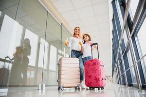 femme avec peu fille dans international aéroport. mère avec bébé attendre pour leur vol. fille avec sa mère en mangeant bananes. en voyageant avec des gamins photo