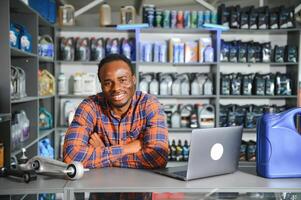 portrait de une Beau africain vendeur dans un auto les pièces magasin. le concept de voiture réparation photo