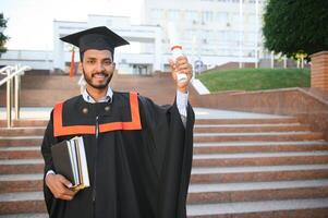 éducation, l'obtention du diplôme et gens concept - content Indien Masculin diplômé étudiant. photo