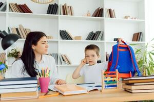 femelle privé tuteur portion Jeune étudiant avec devoirs à bureau dans brillant enfant pièce photo