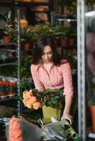 mignonne fille fleuriste recueille une bouquet de des roses dans une fleur magasin. une magnifique fleuriste crée une composition de fleurs. fille coupes fleurs et supprime vicié feuilles photo