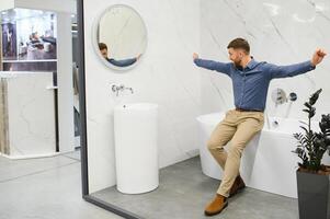 portrait de acheteur dans salle de bains magasin. homme est choisir baignoire pour le sien appartement photo