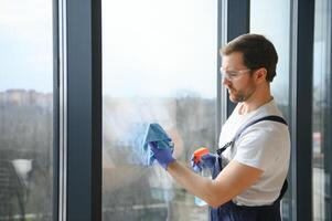 un employé de une professionnel nettoyage un service lavages le verre de le les fenêtres de le bâtiment. vitrine nettoyage pour magasins et entreprises. photo