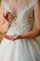 magnifique la mariée dans blanc mariage robe met sur boucle d'oreille. photo