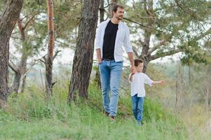 content père et fils séance dans le parc. souriant Jeune homme dépenses temps ensemble avec le sien fils. photo