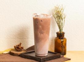 glacé ovale latté thé servi dans jetable verre isolé sur en bois planche côté vue de taiwanais la glace boisson photo