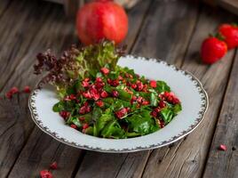 rocca salade avec fraise et Grenade sauce servi dans une plat isolé sur en bois Contexte côté vue photo