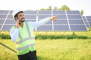 portrait Jeune Indien technicien ou directeur portant formel chiffons permanent avec solaire panneau. renouvelable énergie, homme permanent franchi bras, copie espace photo