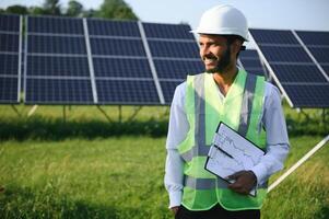 portrait Jeune Indien technicien ou directeur portant formel chiffons permanent avec solaire panneau. renouvelable énergie, homme permanent franchi bras, copie espace photo