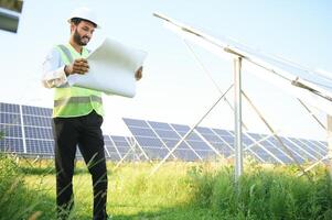 portrait Jeune Indien technicien ou directeur portant formel chiffons permanent avec solaire panneau. renouvelable énergie, homme permanent franchi bras, copie espace photo