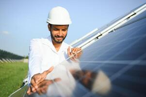 portrait Jeune Indien technicien ou directeur portant formel chiffons permanent avec solaire panneau. renouvelable énergie, homme permanent franchi bras, copie espace photo